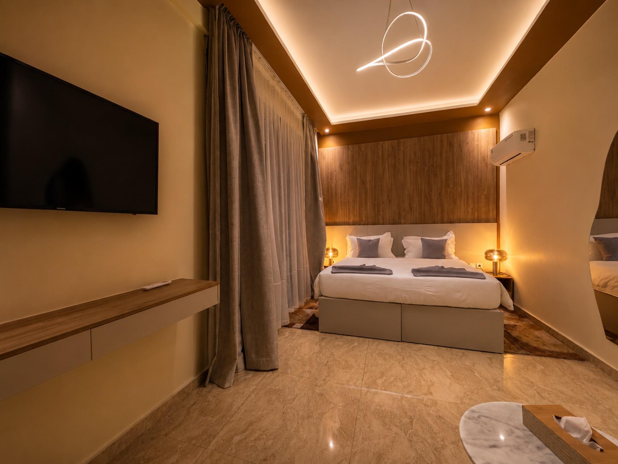 Suite Azur — une chambre, tête de lit en bois et écran mural, le soir