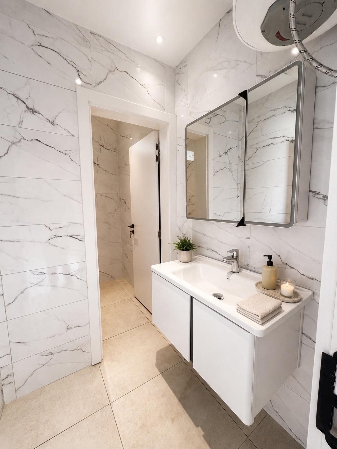 La salle d'eau du spa SO'MOON : vasque, miroirs et douche en marbre blanc