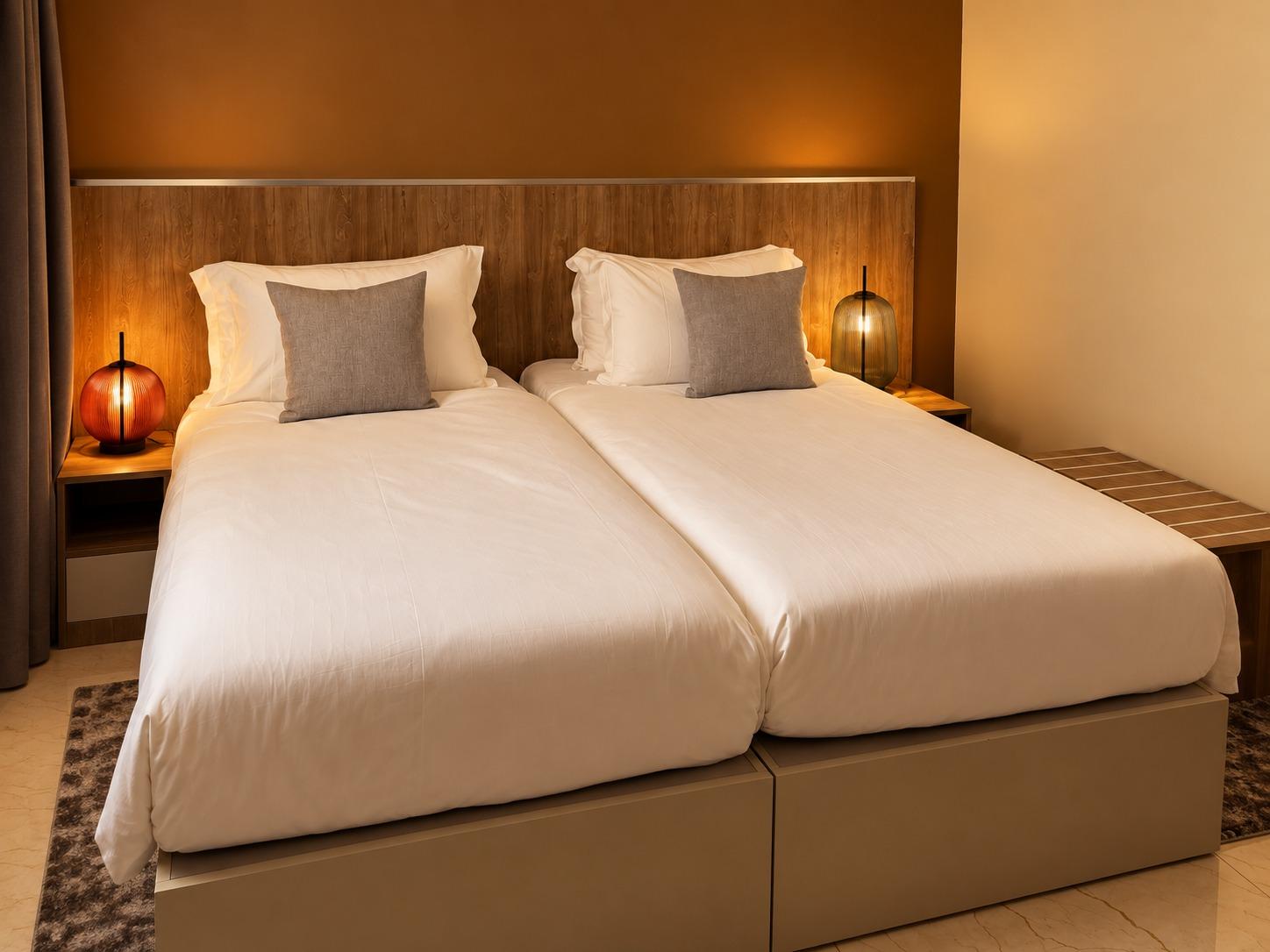 Chambre Twin — les deux lits et les lampes de chevet, mur ocre