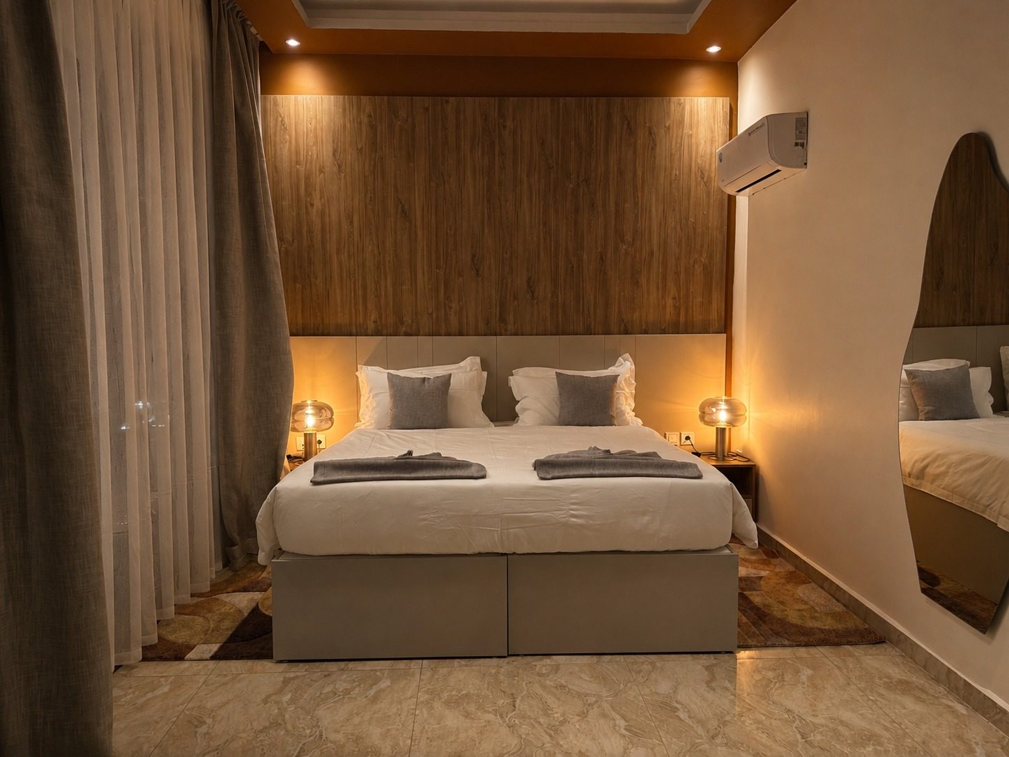Suite Azur — une chambre, tête de lit en bois chaud et miroir ovale